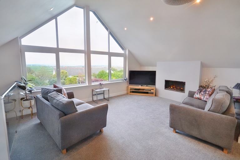 A beautful large lounge with a huge a frame shaped large picture window, professionally enhanced and looking like a professional photo