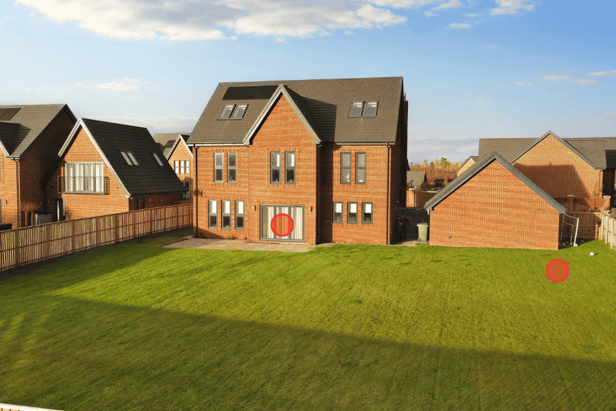 Elevated aerial-style view of a large detached new build residential property with a large grassy area in the foreground and blue skies in the background