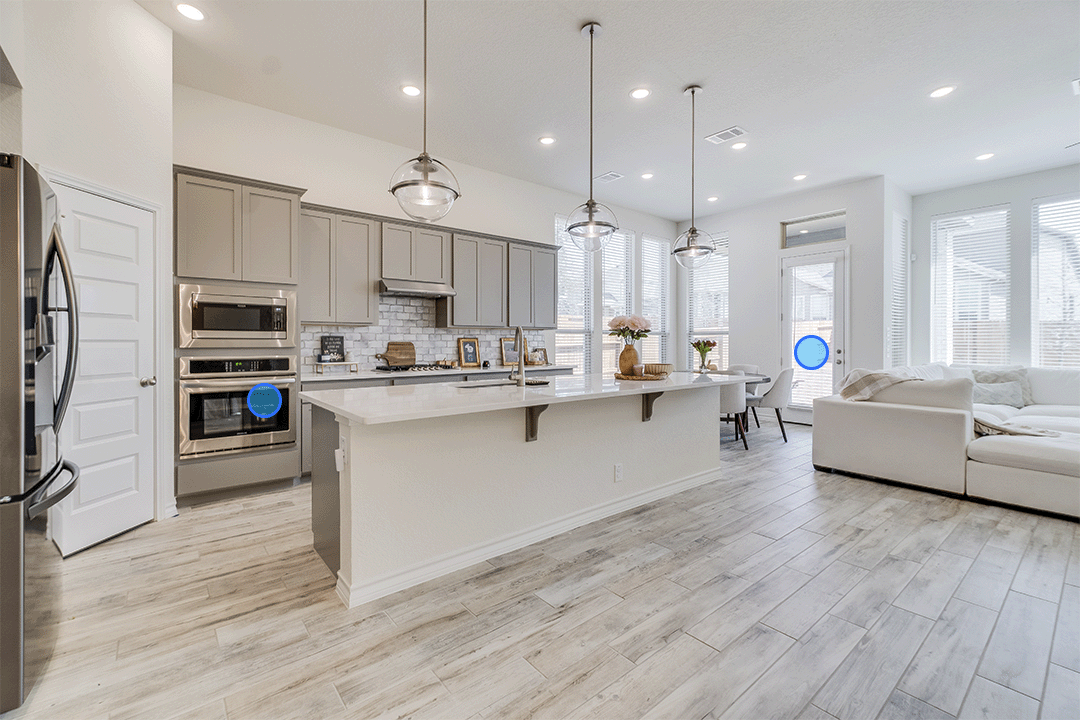 360° virtual tour showing a modern open-plan kitchen and living area with a glossy white island and a large white sofa, and white and grey laminate flooring.