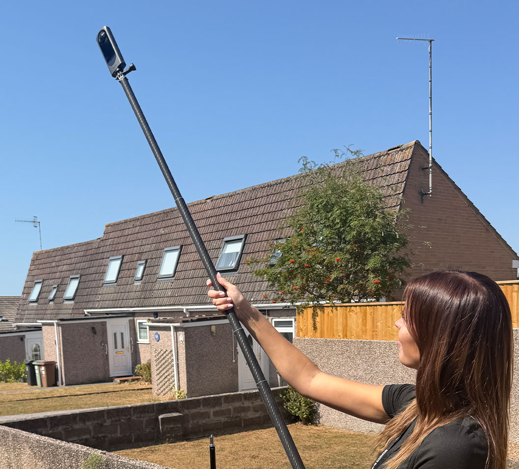 Estate agent extending a camera tripod for an elevated image.