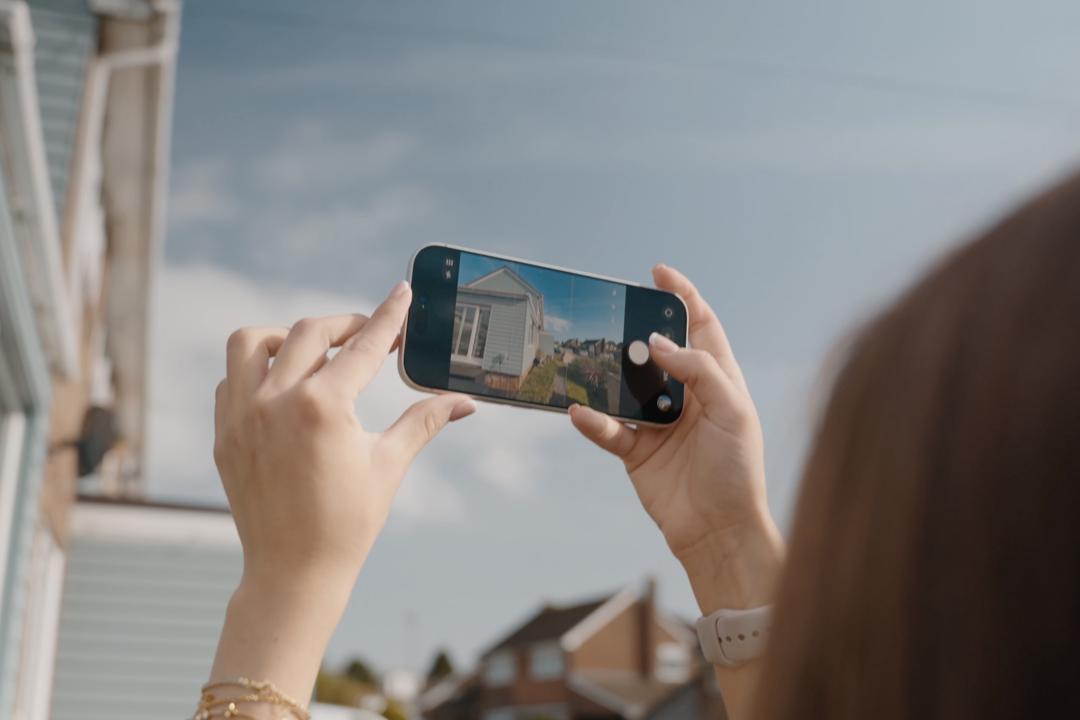 An estate agent taking a photo of a property using a mobile phone.