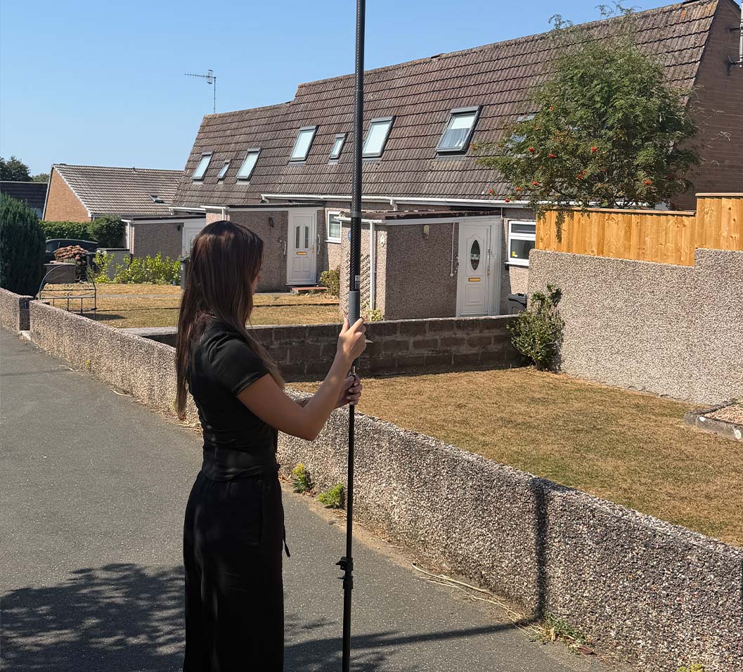 Estate agent attaching an aerial pole to a camera tripod.